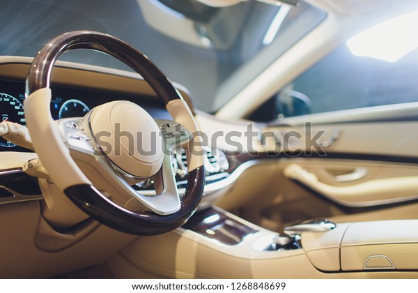 White leather\
interior of the luxury modern car. Leather comfortable white seats\
and multimedia. Steering wheel and dashboard. Automatic gear stick.\
Modern car interior\
details.