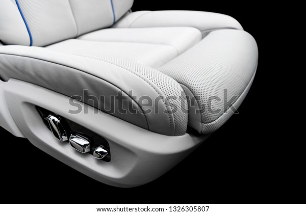 White leather interior of the luxury modern car.\
Perforated white leather comfortable seats with stitching isolated\
on black background. Modern car interior details. Car detailing.\
Car inside