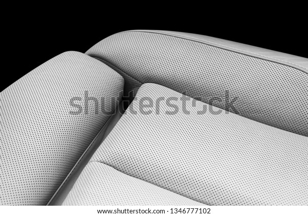 White leather interior of the luxury modern car.\
Perforated white leather comfortable seats with stitching isolated\
on black background. Modern car interior details. Car detailing.\
Car inside