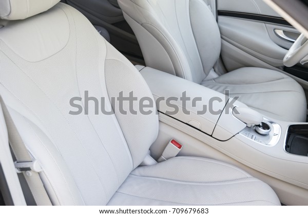 White leather interior\
of the luxury modern car. Leather comfortable white seats and\
multimedia. Steering wheel and dashboard. automatic gear stick. Car\
interior details