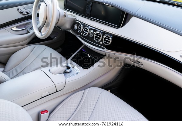 White leather\
interior of the luxury modern car. Leather comfortable white seats\
and multimedia. Steering wheel and dashboard. Automatic gear stick.\
Modern car interior\
details
