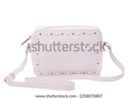 White leather women's bag with shoulder strap and zipper decorated with gold metal and pearl rivets isolated on a white background. Stylish accessories concept. Mock-up for advertising poster.
