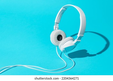 White levitating headphones. Isometric view of headphones on turquoise blue background. Dj headphones with cable.