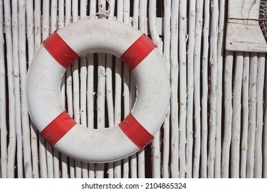White life ring buoy with red strips hanging on white bamboo wooden wall background, mock up. Life rescue concept.