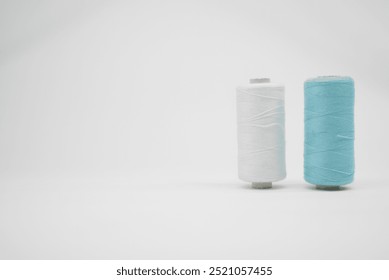 White and light blue thread spools on a white background - Powered by Shutterstock