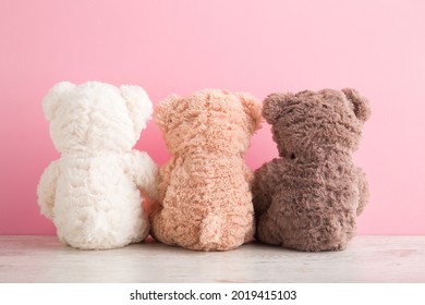 White, Light Brown And Dark Brown Teddy Bears Sitting On Table At Pink Wall Background. Pastel Color. Togetherness And Friendship Concept. Back View. Closeup.