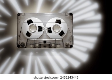 White light rays projection background, photographed with the help of a gobo mask with a retro audio cassette in 1980s disco music style.