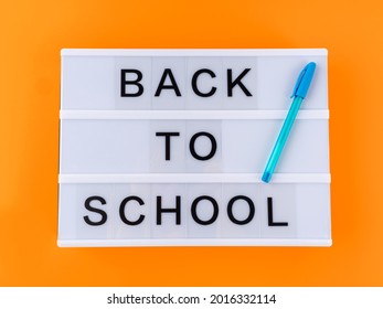 White lightbox with back to school text on yellow background with blue pen. Starting a new school year concept