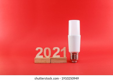 White Lightbulb Standing Next To Number 2021 On The Wooden Stick.  New Year Resolutions Concept