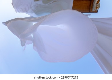 White Linen Drying On Clothesline In Fishing Village Of Symi, Island In Greece. Snow-white Sheets Scatter In Wind. Bottom View. High Quality Photo