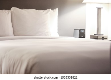 White Lines On A Bed In A Hotel Suite Room In Phoenix, Arizona. Nightstand With A Digital Clock And A Lamp To The Right.