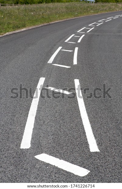White lines painted on a road to slow traffic down on a\
curve. 