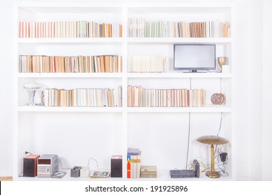 white living room with modern wooden white bookshelf and different books inside, domestic atmosphere, library background indoors, clean and modern decoration