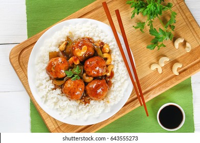 White Long Grain Rice With Chicken Or Turkey Meatballs Stewed With Green Bell Pepper, Onion, Soy Sauce, Chinese Cooking Wine And Spices On Plate On Wooden  Board With Chopsticks, View From Above