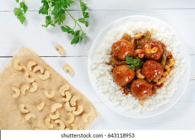 White Long Grain Rice Topped With Chicken Or Turkey Meatballs Stewed With Green Bell Pepper, Onion, Soy Sauce, Chinese Cooking Wine And Spices I On White  Plate On Old Wooden Table, View From Above