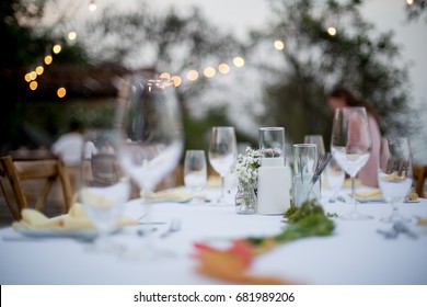 A White Long Table Setting For Outdoor Wedding Dinner With Wine Glasses And Decoration