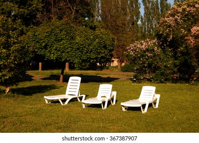 White loungers on green grass in front of country cottage - Shutterstock ID 367387907