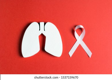 White lung cancer awareness ribbon and lung symbol on red background. November lung cancer awareness month. Healthcare and medicine concept. 