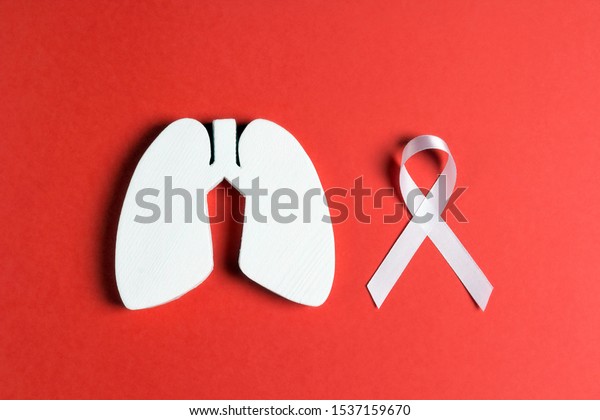 White lung cancer awareness ribbon and lung\
symbol on red background. November lung cancer awareness month.\
Healthcare and medicine concept.\
