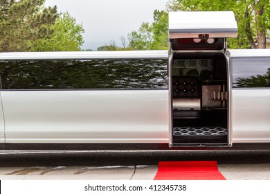 White Luxury Limousine With Open Up Door And Red Carpet Leading To.