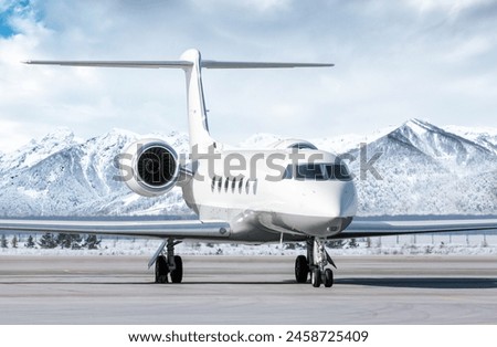 White luxury private jet on airport apron in winter on the background of high picturesque snow capped mountains