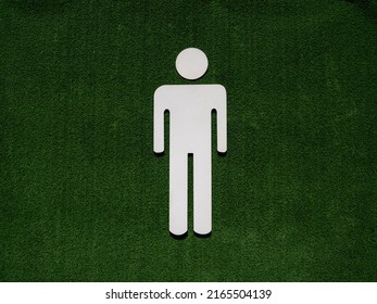 White Male Toilet Symbol On Green Artificial Grass Field Background