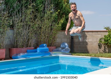 White Man With A Funny Expression Takes A Cannon Ball Dive In A Swimming Pool On A Sunny Day