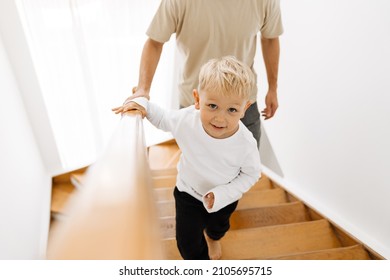 White Man And His Son Coming Up Wooden Stairs At Home