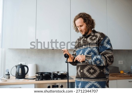 White man home cook checking jar label in cozy kitchen