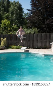 White Man Jumping Into An Outdoor Swimming Pool In The Summer. Man Doing Cannon Ball Into Backyard Swimming Pool On A Sunny Day.  Jumping Off Diving Board Doing Cannon Ball Into A Pool.