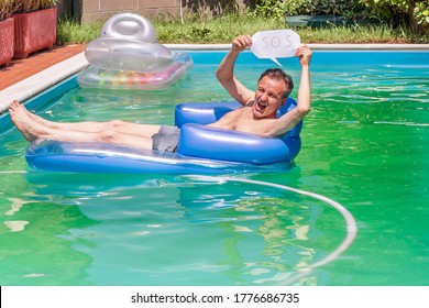 A White Man On An Inflatable Mattress In A Swimming Pool Holds The S.O.S. To Ask For Help