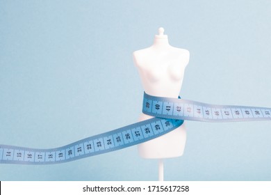 white mannequin wrapped in blue measuring tape, blue background, weight loss concept, copy space, diet, slimming and slimness concept