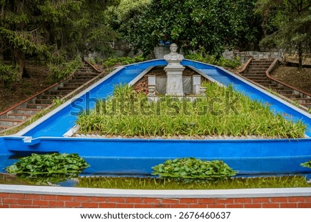 A white marble bust monument set above a blue decorative fountain and surrounded by greenery in the spa park of Termal, Yalova, Türkiye.