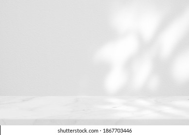 Weißer Marmortisch mit Baumschatten auf Konkreter, Texturhintergrund, geeignet für Produktpräsentationshintergrund, Anzeige und Aufziehen.