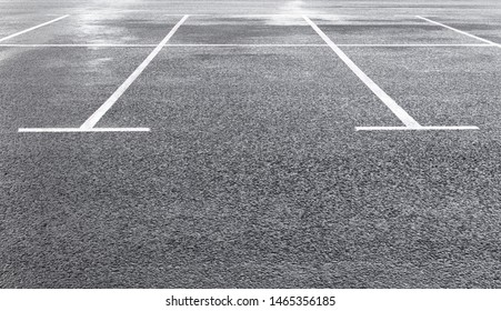 White Marking Lines Of Parking Spots On Wet Asphalt Surface Of Empty Car Park. Copy Space