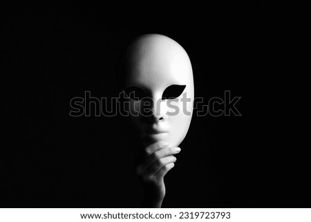 White mask in hands. Black and white Halloween concept portrait