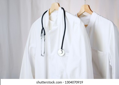 White Medical Doctor Or Physician Lab Coats With Stethoscope Hanging On Clothes Hangers, Copy Space, Selected Focus