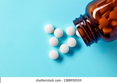 White medical pills and tablets spilling out of a drug bottle. Macro top down view with copy space. 