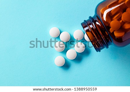 White medical pills and tablets spilling out of a drug bottle. Macro top down view with copy space.  Stock fotó © 