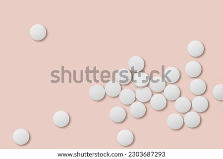 White medicine pills on pink background closeup.