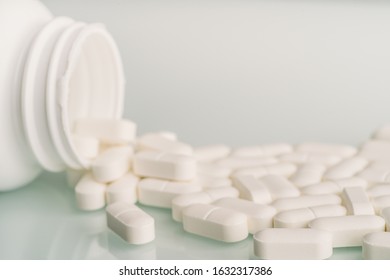 White Medicine Tablets Spilled On Table From Pill Bottle. Medications Drugs Or Supplements Or Opioid Addiction From Pain Killers, Macro With Selective Focus.