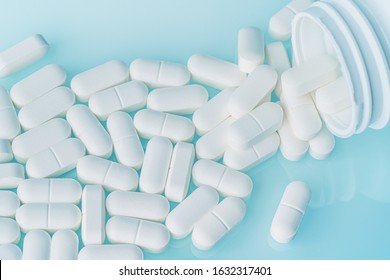 White Medicine Tablets Spilled On Table From Pill Bottle. Medications Drugs Or Supplements Or Opioid Addiction From Pain Killers, Top View.