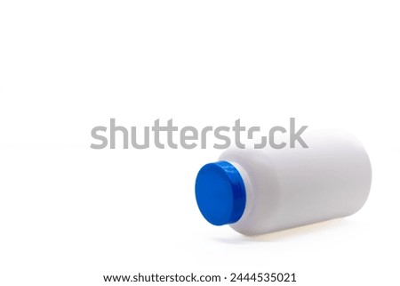 White medicine or vitamin bottle with blue lid lying down and isolated on white background with copy space