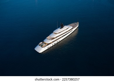 White mega yacht at sunset top view. Large innovative modern yacht anchored in the open sea aerial view.