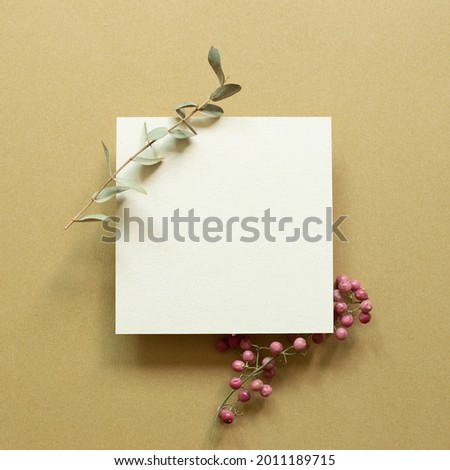 White memo pad with eucalyptus leaf and red fruit on brown background. top view, copy space