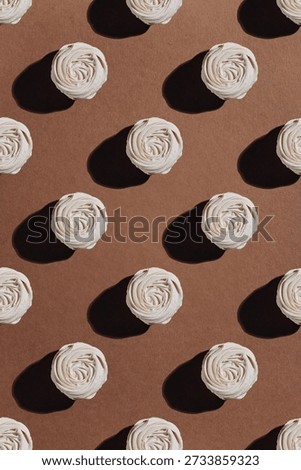 White meringue rosettes pattern on brown kraft paper with hard sunlight shadows