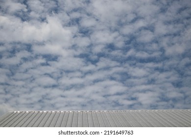 White Metal Roof Of A Methos House On A White Sky Background With Scattered Clouds