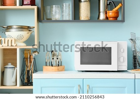 White microwave oven on blue counter in stylish kitchen