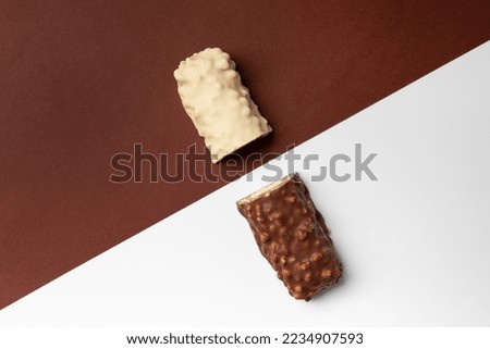 White and milk cut bar on a colored background top view. Conceptual representation of two opposites in the chocolate theme. Two halves of a chocolate bar on contrasting backgrounds