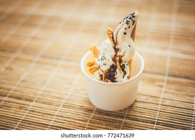 White Milk Soft Serve Ice Cream In Plain White Paper Cup. Cornflake And Chocolate Sauce Topping.